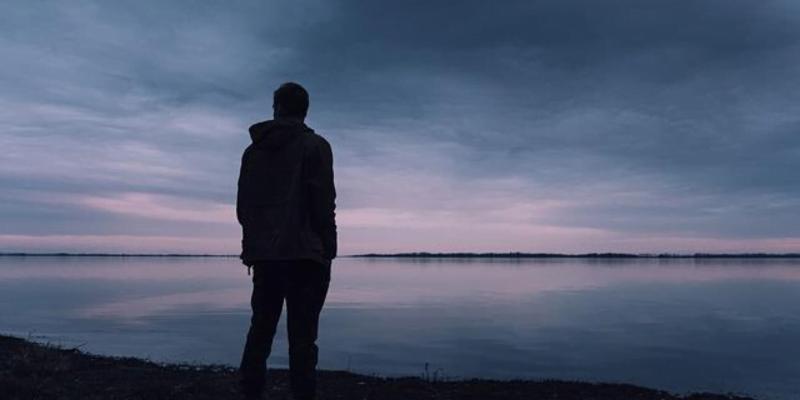 A man by the water takes a moment of quiet reflection to accept what is.